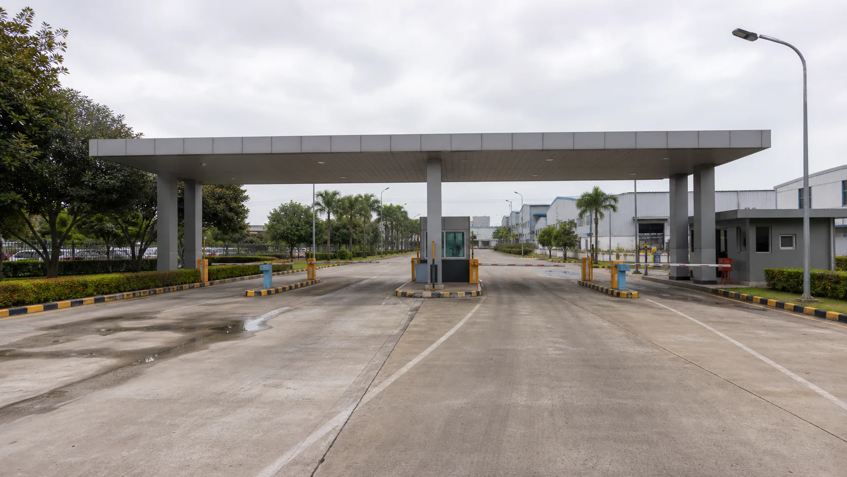gerbang kawasan industri dengan beberapa lajur kendaraan, barrier, dan pembaca akses.