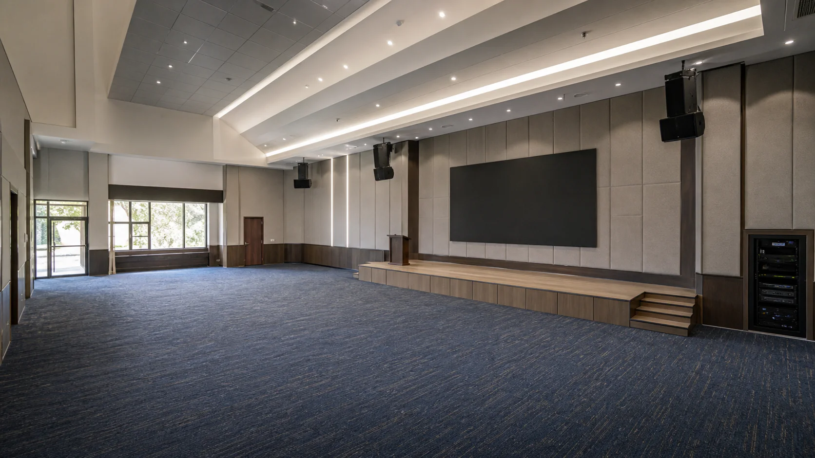 a large multipurpose hall with integrated sound, display, and AV rack systems.